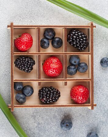 berries in a wooden box on a gray background, strawberries, blueberries, blackberries, berries in a separate boxの写真素材