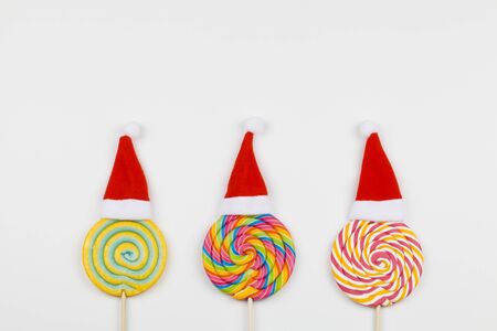 rainbow color lollipops with santa claus hats on white background, copy space isolated on white, christmas backgroundの写真素材