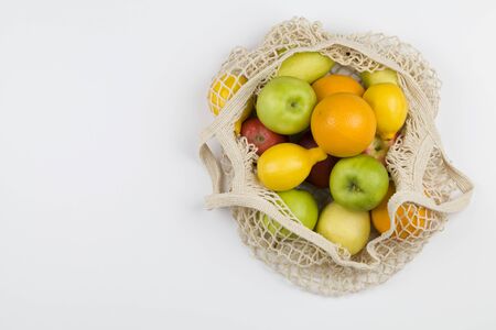 Mesh shopping bag with fruits apples, oranges, lemon and pears on white background. Top view, flat lay, copy space. Zero waste, eco friendly concept.の写真素材