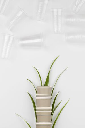 eco friendly disposable, compostable, recyclable paper cups with plant branches and plastic glasses on white background. assembled together in one another. copy space top view. zero waste conceptの写真素材