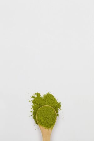 Wooden spoon with green matcha tea powder on white background, closeup space for text top viewの写真素材