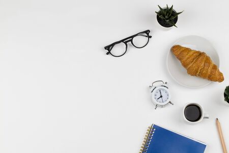 Businessman morning with blue notebook, cup of coffee, croissant , clock and glasses on white background top view mockup copy space flat layの写真素材