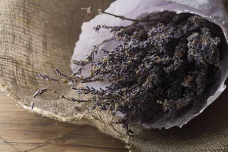 lavender bouquet wrapped in sackcloth and paper on wooden backgroundの写真素材
