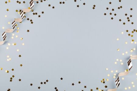 Festive party border or frame of silver spiral streamers and confetti on blue background, copy space top view flat lay close upの写真素材