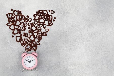 Time concept. alarm clock in blue background with red heart. minimalism style. space for text. Valentines day background. design element for greeting cards, saleの写真素材