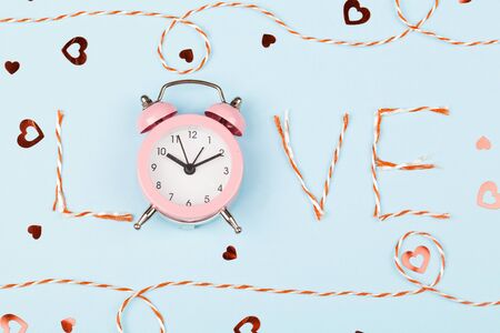 Valentines day composition with Love word and confetti on blue background. Flat lay, top view....