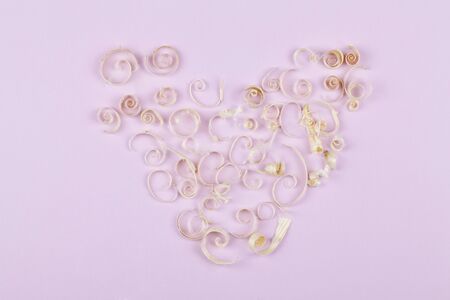 heart from wood shavings on pink background, concept for valentine's day . top view flat lay