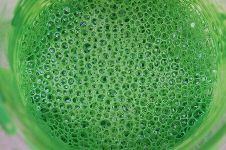 top view of glass with green paint with bubbles. abstract background