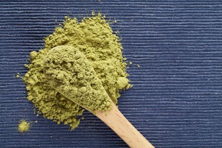 matcha green tea powder in wood spoon on blue background. top view copy space healthy food conceptの写真素材