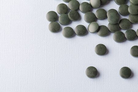 green round tablets of spirulina on white background close up copy spaceの写真素材