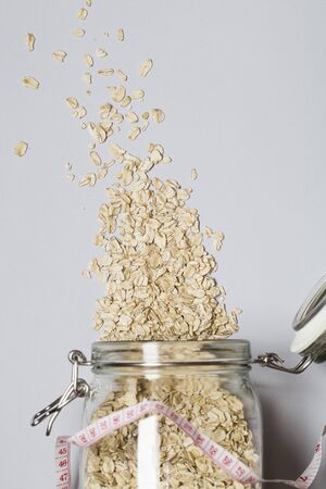 Natural oatmeal and measurement on gray background . Oatmeal in a glass pot.healthy breakfast concept . top view flat lay copy spaceの写真素材