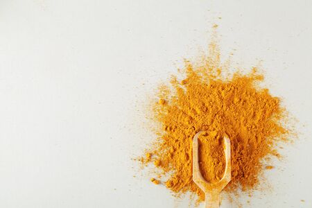 turmeric powder in wood spoon on gray background, indian spice, healthy seasoning ingredient for vegan cuisine copy spaceの写真素材