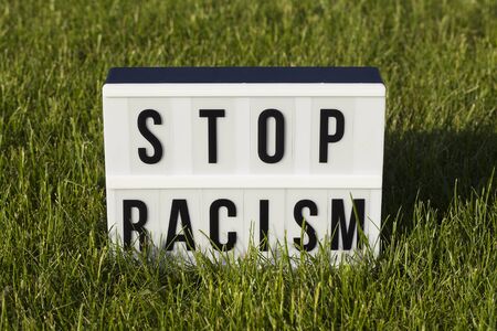 light box with text STOP Racism on green grass backgroundの写真素材