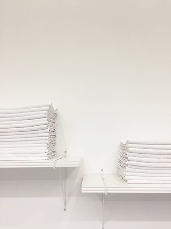 Stack of clean white towels on shelf on white background copy cpace monochrome
