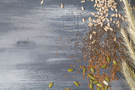 Flax sunflower chia, pumpkin seeds and wheat ears on blue background. Healthy superfood concept copy...