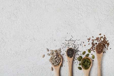 Flax sunflower chia, pumpkin seeds in wooden spoon on white background. Healthy superfood concept copy spaceの写真素材