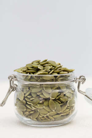 organic pumpkin seeds in glass jar on gray background. Concept of healthy diet. Super food. copy...
