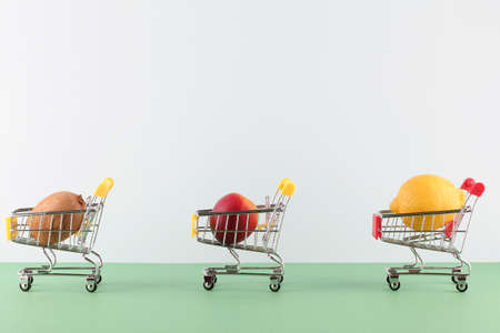 Basket with fruit located at distance from each other on white and green background. social distance in public placesの写真素材