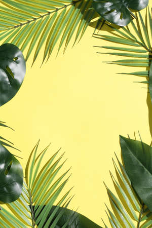 Creative layout from tropical leaves and palms on bright yellow background with deep shadows....