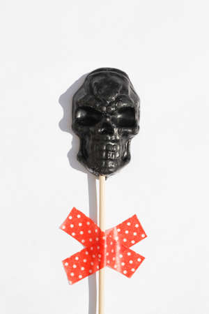 black lollipop in form of skull on white background .. Creative Halloween minimal concept. flat lay top viewの写真素材