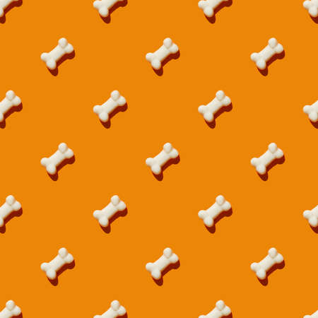 pattern made with marmalade in form of bone on bright orange background. Funny holiday flat lay...