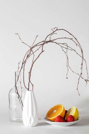 tree branches in vases hanging on fruit lemon, orange, strawberry. autumn still life. autumn...