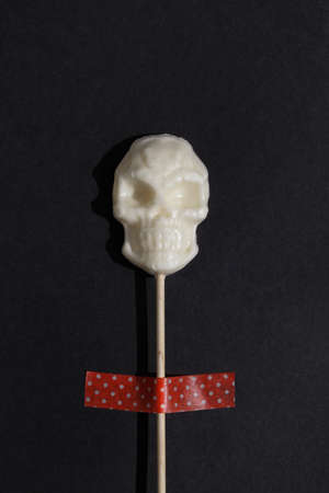 white lollipop in form of skull on black background. Creative Halloween minimal concept. flat lay top viewの写真素材