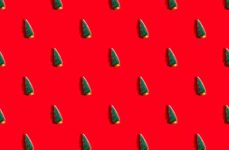 Minimal pattern background of green Christmas trees on red background. New Year concept.の写真素材