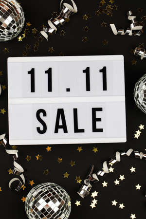 11.11 sale text on white lightbox, holiday ribbon, small stars and disco balls on blackの写真素材