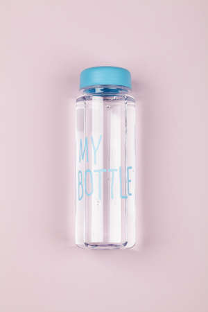 reusable water bottle with blue cap on pink background. Healthy lifestyle and fitness concept. flat lay top viewの写真素材