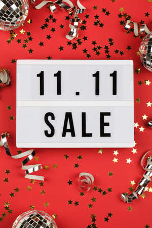 11.11 sale text on white lightbox, holiday ribbon and box on red background. Online shopping, singles day sale concept. Top view copy spaceの写真素材