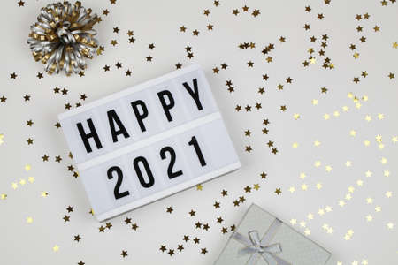 lightbox with words happy 2021, gift box and holiday confetti on white background. top view. New year celebration. Happy New Year 2021 concept.の写真素材
