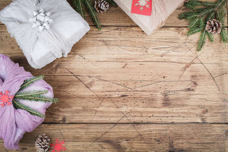 Christmas and zero waste, eco friendly packaging. Fabric wrapped gifts on brown wooden table, ecological Christmas holiday concept, eco decorの写真素材