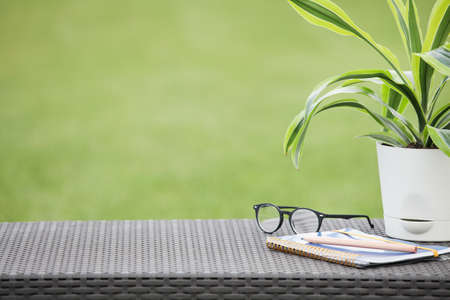 Working place with notebook, glasses, pencil and flower on green background. Freelancer working place. copy spaceの写真素材