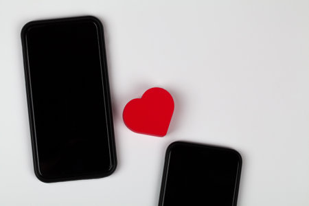 Red heart and two mobile phones on white background. Internet dating, copy space, Valentines day concept.の写真素材
