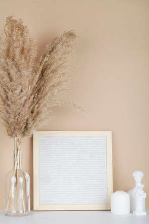 Dried pampas grass in vases, candles and felt letter board on beige background, interior, home design. Art concept. copy spaceの写真素材