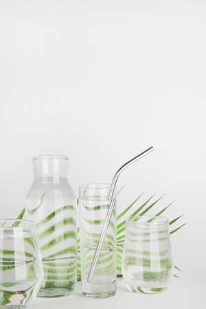palm leaf distorted through water in glasses and bottle with reusable tube on white background. Home decor, eco friendly, pure water concept.copy spaceの写真素材
