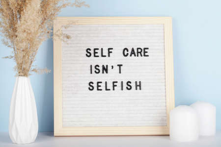 Dried pampas grass in vases, candles and felt letter board with phrase self care is not selfish on blue and white background.concept of mental healthの写真素材