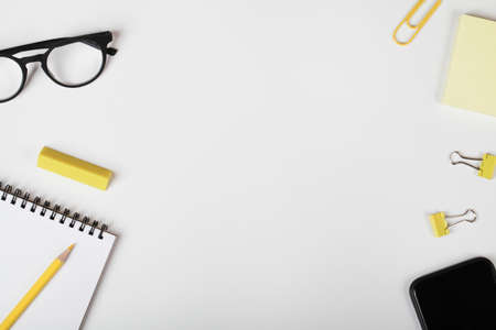 office table desk, workspace with mobile phone, notebook, yellow pencil, office supplies and eyeglass. Minimal concept. Flat lay, top view. copy spaceの写真素材
