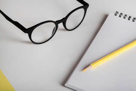 office table desk, workspace with notebook, yellow pencil and eyeglass. Minimal concept. Flat lay, top view, copy space.の写真素材