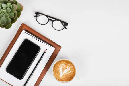 office table desk, workspace with mobile phone, notebook, pencil, green plant, coffee and eyeglass. Business background. Flat lay, top view.copy spaceの写真素材