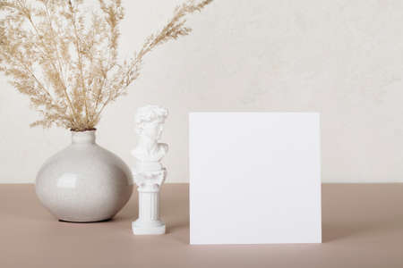 Blank paper card, invitation mockups with small statue and pampas grass in vase on white and beige...