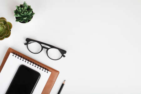 office table desk, workspace with mobile phone, notebook, pencil, green plant and eyeglass. Business background. Flat lay, top view. copy spaceの写真素材