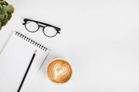 office table desk, workspace with notebook, pencil, eyeglass. coffee and green plant. Business...