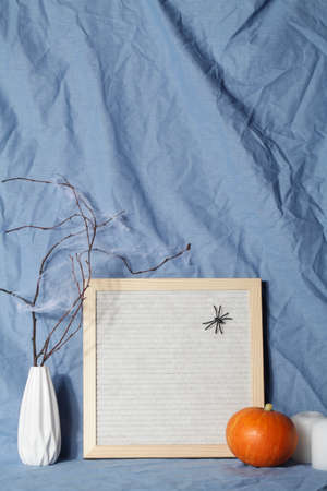 felt letter board with space for text with candle, pumpkin on crumpled blue textile...