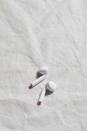 wireless headphones on linen textiles with deep shadow. minimal style concept. boho design