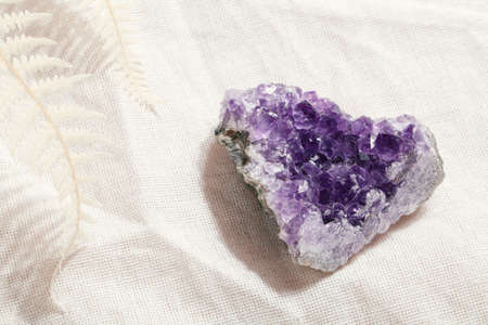 druse raw purple amethyst crystal on piece of stone on gray linen with fern, magic rock for ritual, witchcraft, spiritual practice, meditationの写真素材