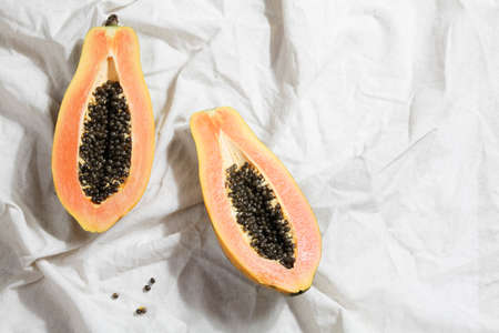 creative food concept with half papaya on crumpled gray linen. Flat lay top view. minimalist...