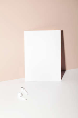 paper card note with headphones on beige background with shadow. copy space. business mock up. card with place for your text.の写真素材