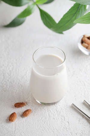Vegan almond milk in glass with nuts and green plant on white background. Healthy vegetarian food. selective focus. Non dairy alternative milkの写真素材
